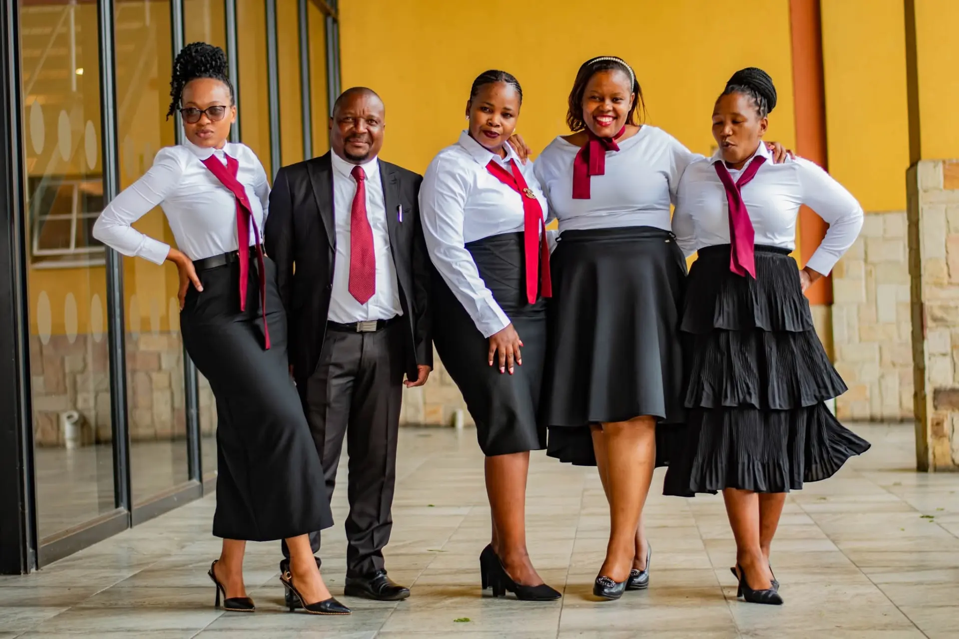 Five staff members in coordinated white, black and maroon attire