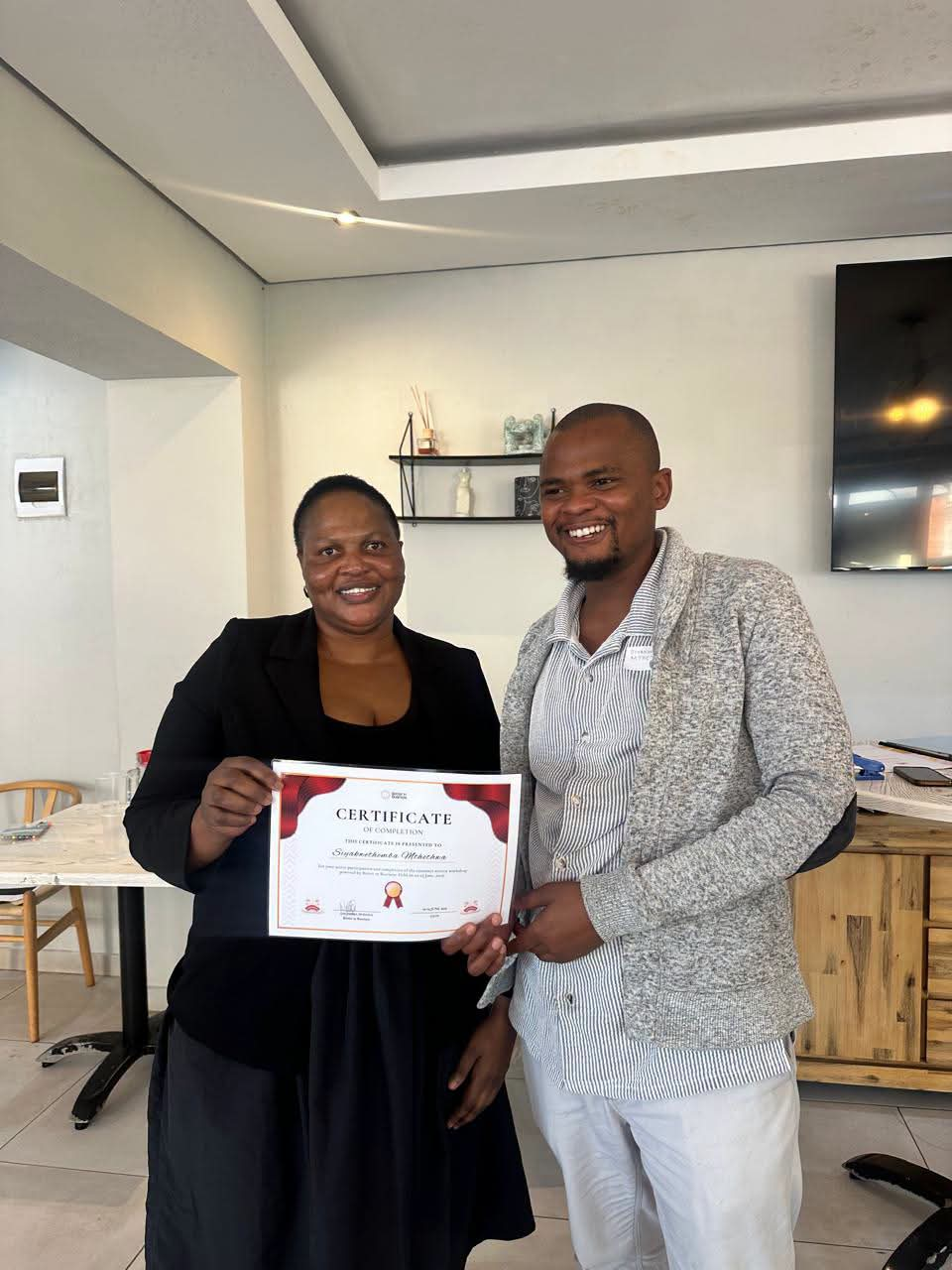 Staff member presenting a Certificate of Completion to a colleague