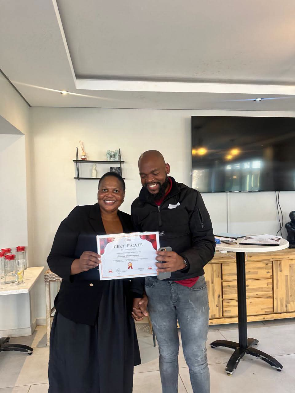 Staff member presenting a Certificate of Completion to a colleague