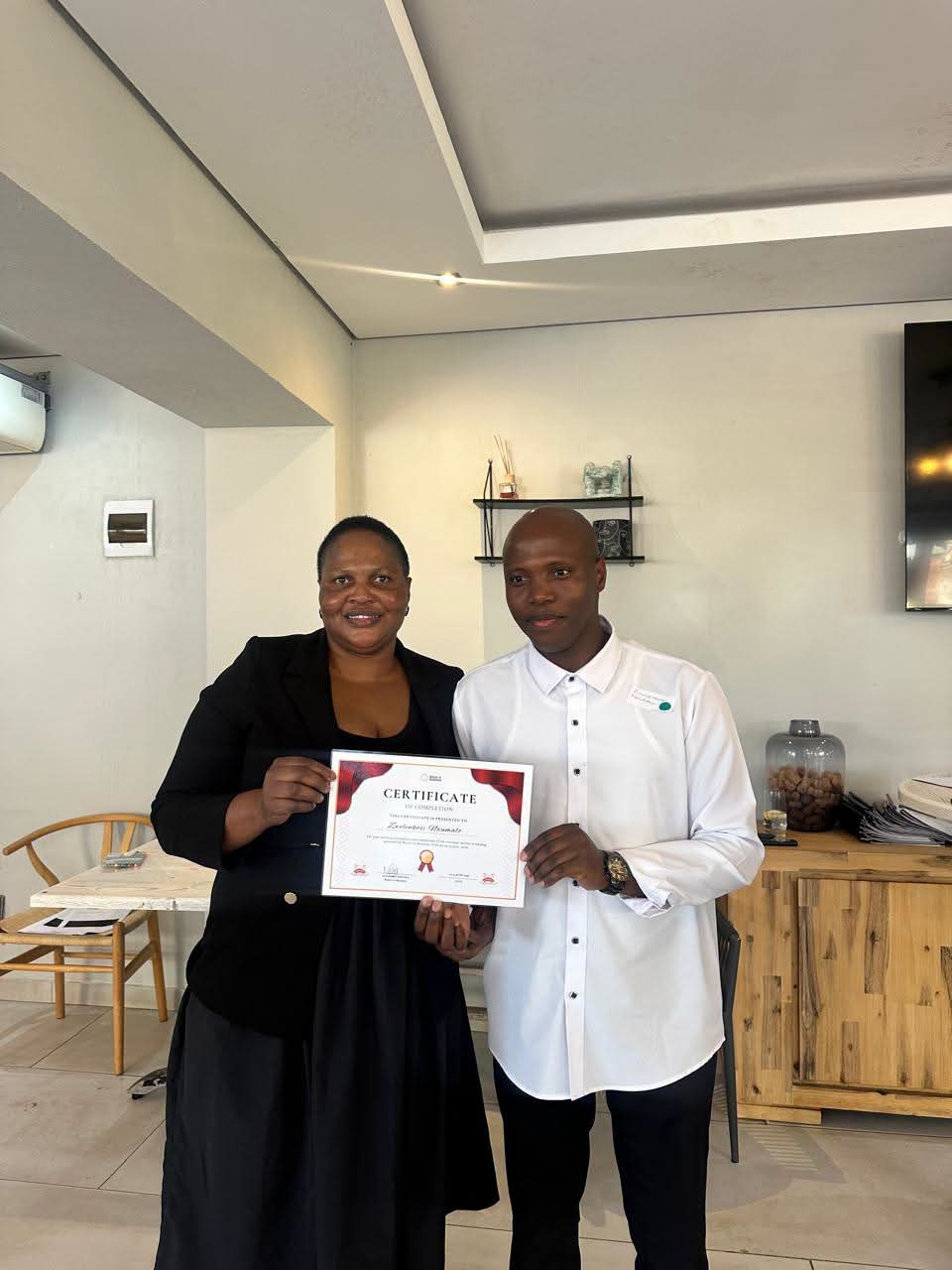 Staff member presenting a Certificate of Completion to a colleague