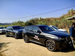 Several branded black SUVs parked on a dirt area